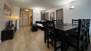 A modern dining area with a long table and multiple chairs, a sofa, and a small side table with decorative lights. - Spacious apartment for 8 people, with balcony and parking in Brides-les-Bains (Brides-les-Bains)