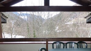 A covered outdoor area with a table and chairs, a view of trees and mountains in the background. - Spacious apartment for 8 people, with balcony and parking in Brides-les-Bains (Brides-les-Bains)