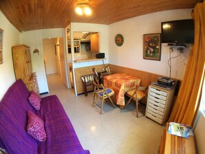A cozy living area with a sofa, a small dining table, and a kitchenette in the background.