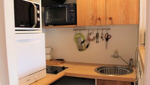A compact kitchen with a microwave, toaster, coffee maker, and a washing machine. - Studio Mountain Getaway with Balcony, Parking, Near Slopes and Shops (Vars)
