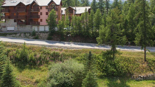 A multi-story building with balconies, surrounded by dense forest and mountains in the background. - Studio Mountain Getaway with Balcony, Parking, Near Slopes and Shops (Vars)