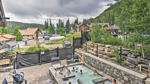 A pool area with people enjoying the water, surrounded by a stone wall and a wooden fence. - Purgatory Resort Condo, Walk to the Chairlift (Durango)