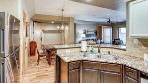 A spacious kitchen with granite countertops, wooden cabinets, and a stainless steel refrigerator. - Purgatory Resort Condo, Walk to the Chairlift (Durango)