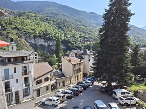 A hotel with a view of a mountainous landscape, parked cars, and a street with buildings.