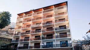 Um hotel com vários andares, varandas, fachada de pedra e céu claro.