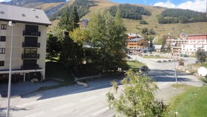 A multi-story building with balconies, a parking lot, and a mountainous backdrop.