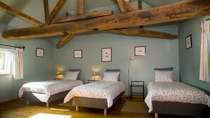 Ein Schlafzimmer mit zwei Einzelbetten, Holzbalken an der Decke und gerahmten Bildern an den Wänden.
