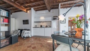 Une cuisine moderne avec des meubles blancs, un four à micro-ondes et une bouilloire. Un coin repas est aménagé avec une table et des chaises en verre.