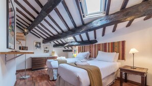Une chambre avec deux lits, des poutres apparentes, une lampe suspendue et une table de chevet.