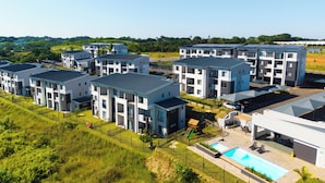 Un moderno complejo de apartamentos con varias edificaciones, piscina y un espacio al aire libre cubierto.
