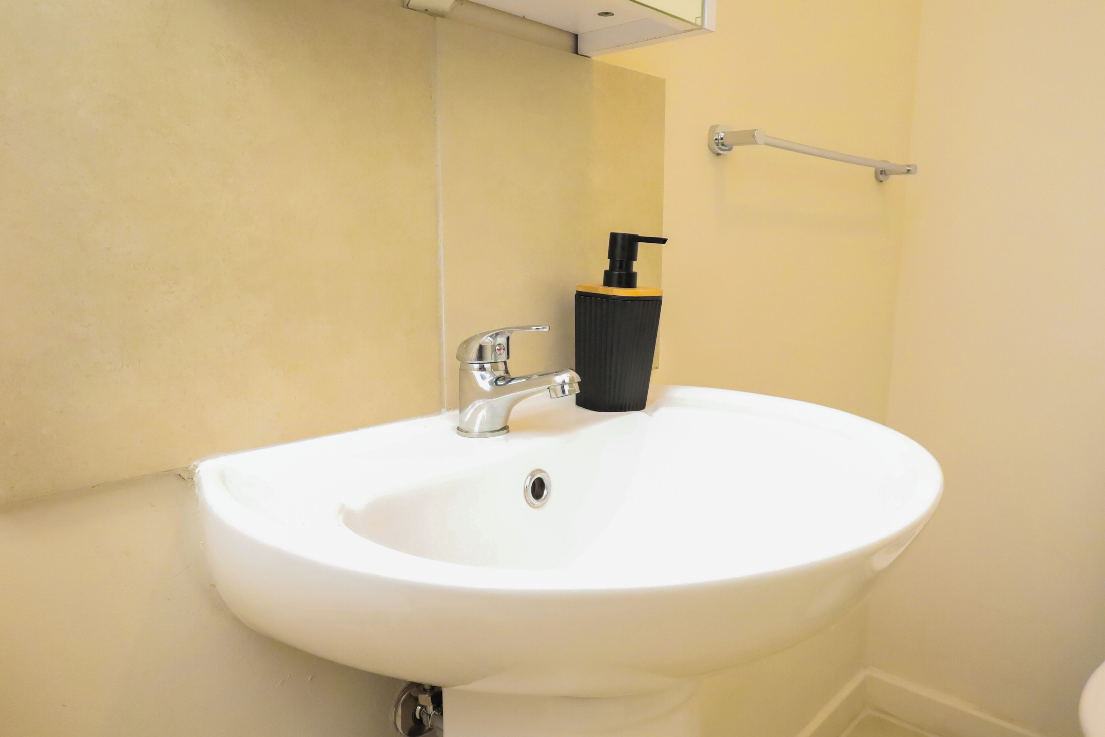 A white bathroom sink with a chrome faucet and a black soap dispenser.