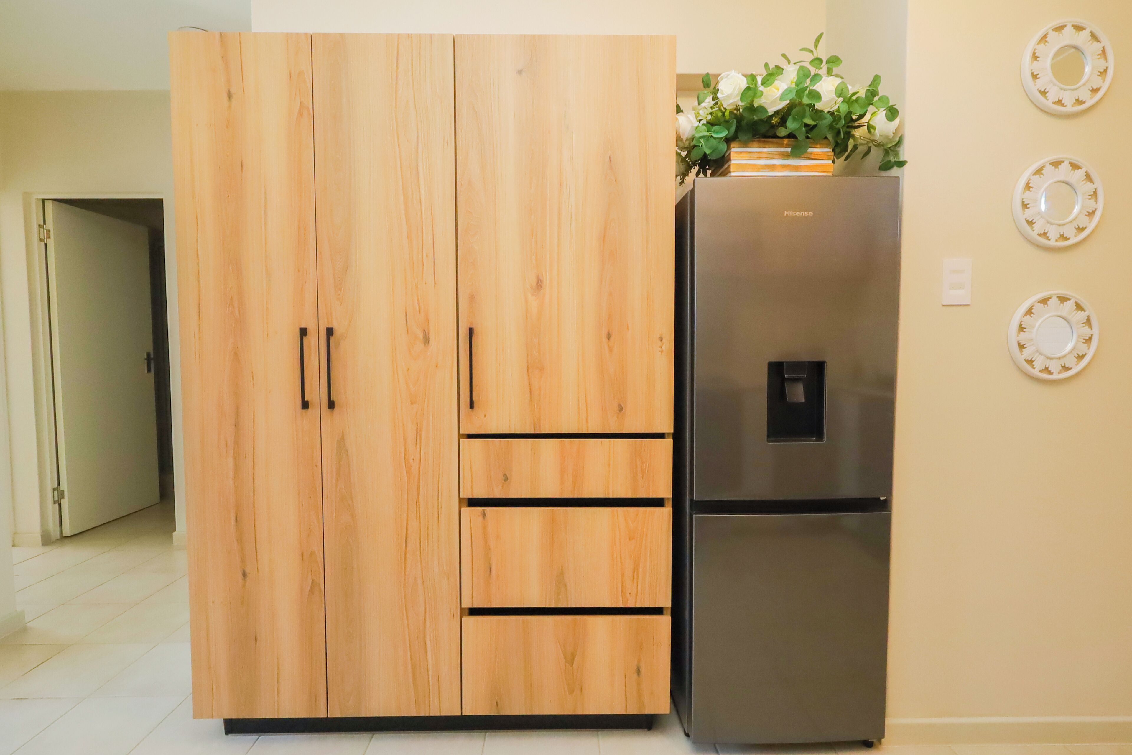 Una cocina con un armario de madera y un refrigerador de acero inoxidable.