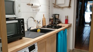 Une cuisine compacte équipée d’un lave-linge, d’un four à micro-ondes, d’une machine à café et d’un évier.