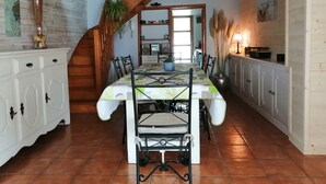 Un espace repas doté d’un plafond en bois, d’un lustre et d’un sol carrelé.