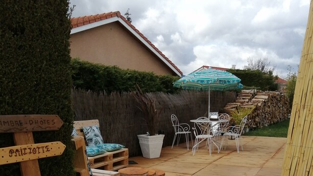 Une terrasse en bois avec des meubles d’extérieur, un arrosoir et des panneaux de signalisation.