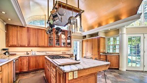 A spacious kitchen with wooden cabinets, a large island, and hanging pots. - Lovely Brookfield Home w/ Private Deck & Views (Brookfield)