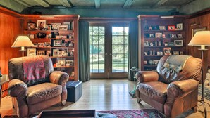 A cozy living room with leather armchairs, a bookshelf, and a large window. - Lovely Brookfield Home w/ Private Deck & Views (Brookfield)