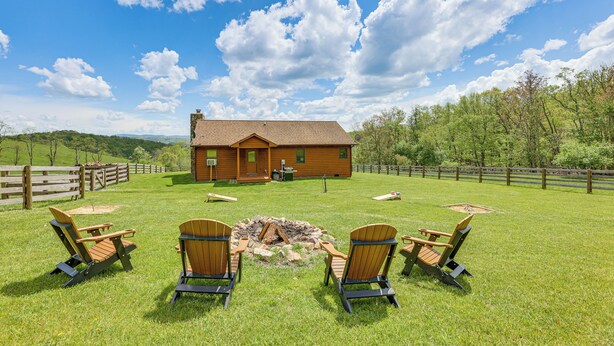 A lodge with a fire pit and four Adirondack chairs in the yard. - Fish, Hike, Hunt: Secluded Cabin in Doe Hill! (Doe Hill)