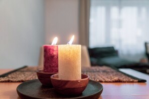 Duas velas em castiçais de madeira sobre um prato escuro.