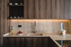 A modern kitchen with wooden cabinets, a countertop, a sink, and a fruit bowl. - Iris & Espera BeachFront Residences,  Sea & City (Rethymno)