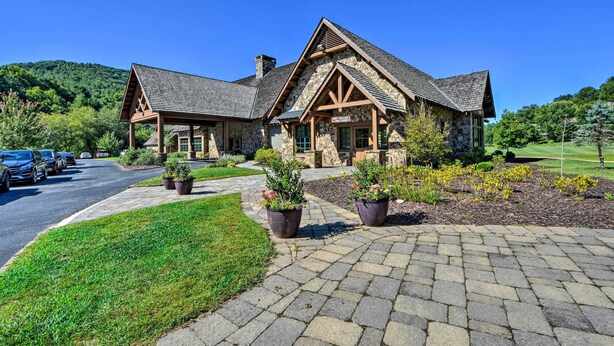 A stone building with a pitched roof and wooden beams, surrounded by a well-maintained lawn and potted plants. - Newly Renovated Sky Valley Condo w/ Mtn Views (Sky Valley)