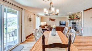 A dining area with a wooden table, chairs, a chandelier, and a stone fireplace. - Newly Renovated Sky Valley Condo w/ Mtn Views (Sky Valley)