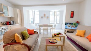 Una sala de estar moderna con sofá, una mesa de comedor y una zona de cocina con microondas.