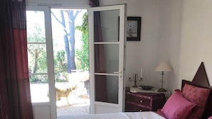 Ein Schlafzimmer mit einem Bett, einem Nachttisch, einer Lampe und einer Glastür, die zu einem Außenbereich führt.