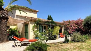 Ein Haus mit Terrasse, Gartenmöbeln und einem Garten.