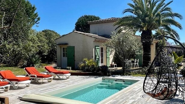 Ein Poolbereich mit Liegestühlen, einem Whirlpool und einem Haus mit einem Ziegeldach.