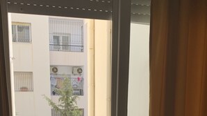 Un balcon donnant sur un immeuble doté de nombreux balcons et sur un arbre.