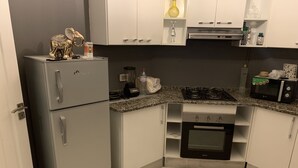Une cuisine compacte équipée d’un réfrigérateur, d’une cuisinière, d’un four et d’un four à micro-ondes.