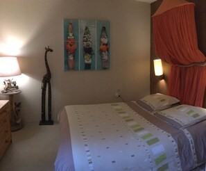 Een slaapkamer met een bed, een girafsculptuur en drie schilderijen aan de muur.