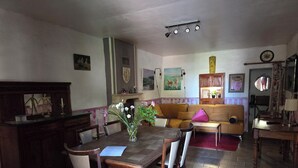 A dining area with a wooden table and chairs, a sofa, and a fireplace. - 9-person country house with small spa (Capestang)