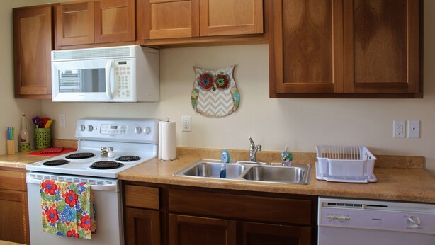 A kitchen with wooden cabinets, a white stove, a microwave, and a dishwasher. - Downtown Charmer-2 bed/2 bath (Fargo)