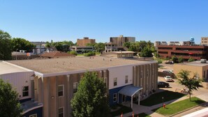 A multi-story building with a flat roof, surrounded by trees and other buildings. - Downtown Charmer-2 bed/2 bath (Fargo)