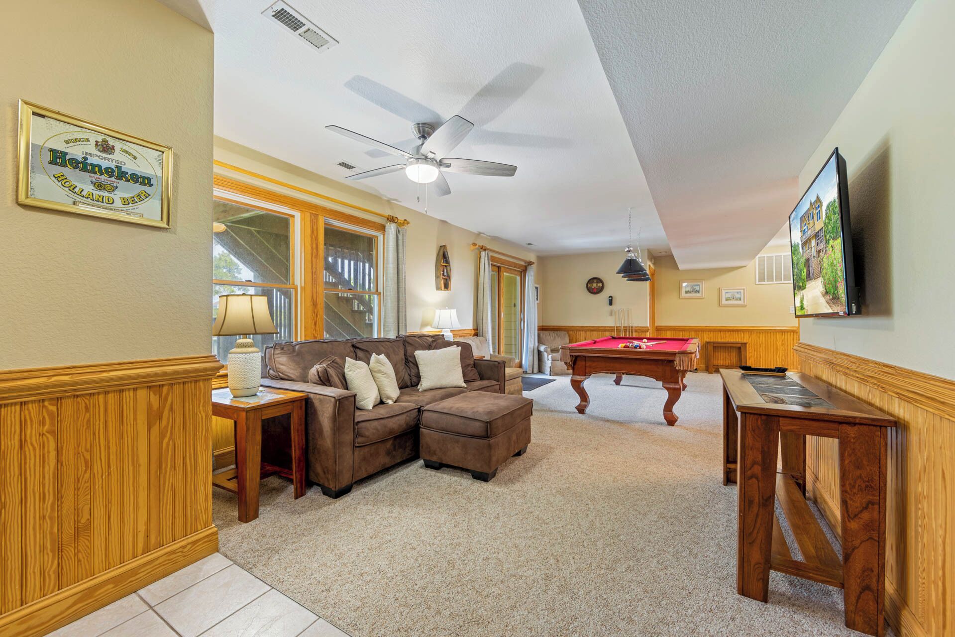 A living room with a brown leather sofa, a pool table, and a ceiling fan.