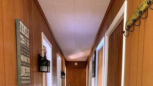 A wooden hallway with a sign on the left wall, a door at the end, and a light fixture on the right. - Rangeley Waterfront Retreat: 4 Bed, 2 Bath, Perfect for Families to Unwind (Rangeley)