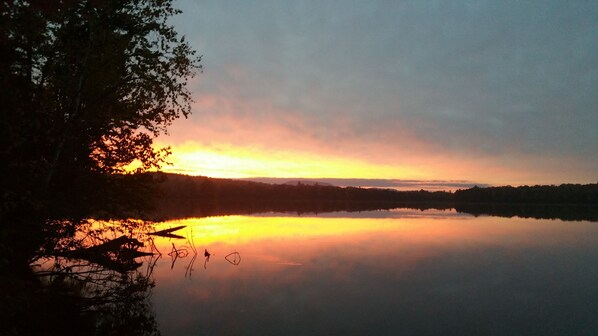 A calm lake at sunrise with trees reflecting the light. - Rangeley Waterfront Retreat: 4 Bed, 2 Bath, Perfect for Families to Unwind (Rangeley)