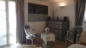A room with a dining table, two chairs, a cabinet, a painting, and a window with curtains. - Almond room with whirlpool bath (Plan-de-la-Tour)