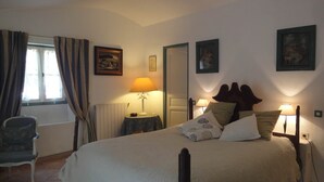 A bedroom with a four-poster bed, a chair, a table with a lamp, and artwork on the walls. - Almond room with whirlpool bath (Plan-de-la-Tour)