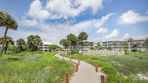A pathway leading to a building with multiple floors, surrounded by greenery and palm trees. - Captiva Beach Villas 🏝 On The Gulf Beach (Captiva)