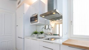 Una cocina moderna con armarios blancos, electrodomésticos de acero inoxidable y encimera de madera.