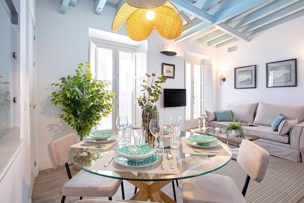 A dining area with a glass table, chairs, and a large plant.