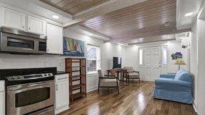 Cocina moderna con electrodomésticos de acero inoxidable, piso de madera y un comedor con sofá azul.