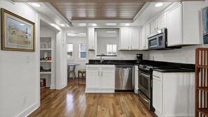 Una cocina moderna con armarios blancos, lavavajillas de acero inoxidable y encimera negra.