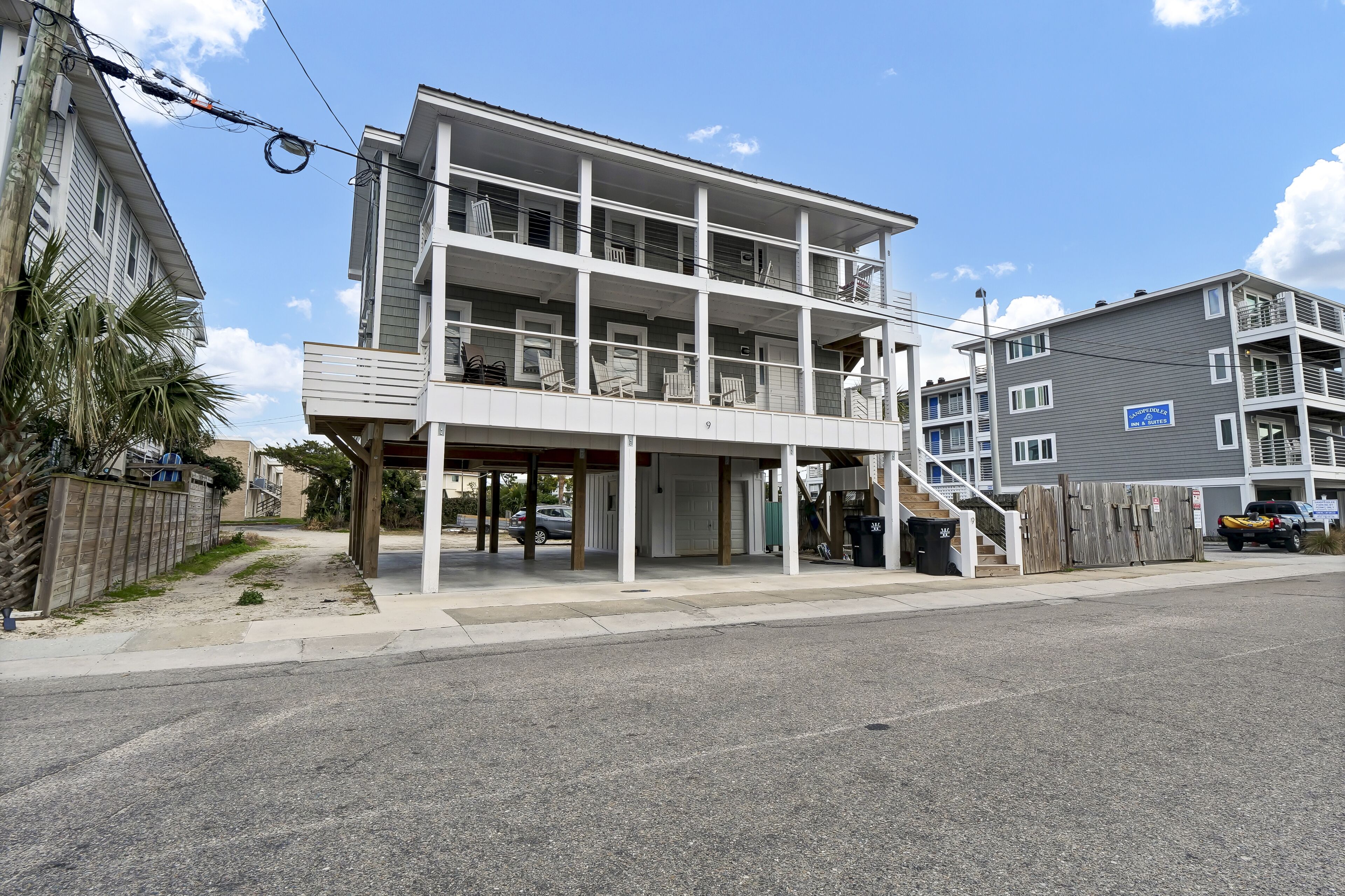 A multi-story building with balconies, a covered entrance, and a sign indicating a business.