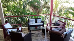 A balcony with wicker furniture, a glass table, and a railing. - Gite T4 MONTANA 200 m2, 7/9 beds, 2 bathrooms and 2 separate toilets, 350 m beach. (Deshaies)
