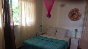 A bedroom with a bed, two bedside tables, a hanging pink canopy, a wall mirror, and a window with curtains. - Gite T4 MONTANA 200 m2, 7/9 beds, 2 bathrooms and 2 separate toilets, 350 m beach. (Deshaies)