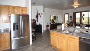 A modern kitchen with stainless steel appliances, wooden cabinets, and a granite countertop. - Saguaro Sunset Retreat (Apache Junction)